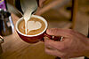Ein Milchkaffee wird zubereitet und serviert