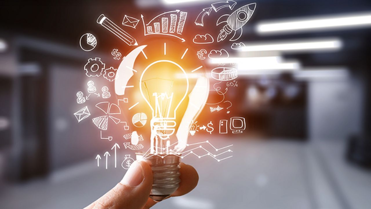 Eine Hand hält eine hell erleuchtete Glühbirne. Ringsherum schweben viele Symbole wie Diagramme und Computer.