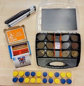 [Translate to Leichte Sprache:] Verschiedene Materialen des Projektes Challenge Inklusion liegen auf einem Tisch. Zu sehen sind ein zusammen geklappter Langstock, ein aufgeklappter Koffer mit Simulationsbrillen für verschiedene Augenkrankheiten, das Kartenspiel "Dumme Fragen gibt es nicht" und ein Hör-Memory-Spiel.